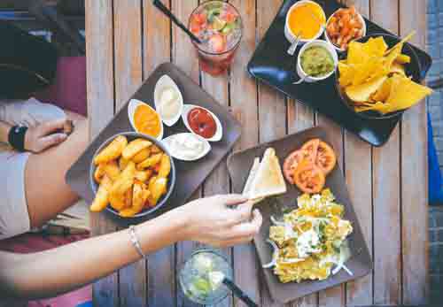 Woman’s Hand Taking Food From Cafe Table With Dips And Drinks
