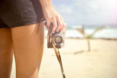 Woman’s Hand Holdig Vintage Camera On Sunny Beach