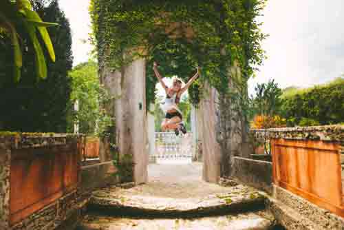 Girl Playfully Jumping For Joy In Summer Garden