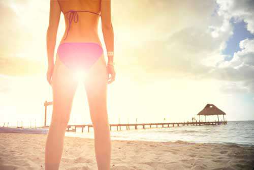 Woman Wearing Bikini On Beach With Sun Flare Between Legs