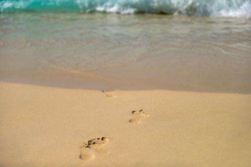 Footprints In Sand Walking Towards Sea