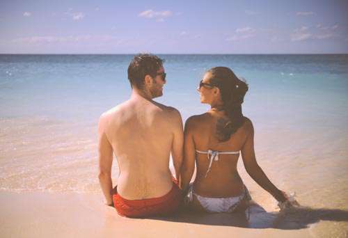 Cute Man And Woman Sitting On A Beach With Sea