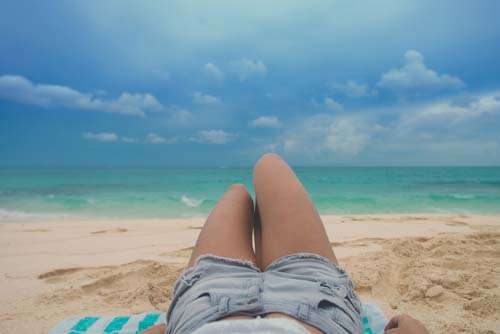 Lifestyle Girl laying on Beach With Jean Shorts
