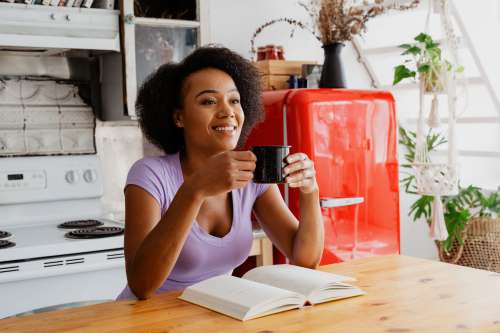 Woman Enjoying Coffee And Book In The Kitchen Photo