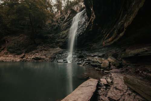 Cascading Waterfall Beside Concaved Rocks Photo
