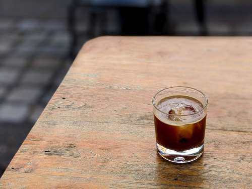 Cold coffee americano with ice cube on a wooden table