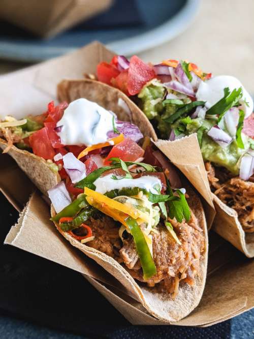 Tacos with pulled pork, fresh vegetables and cream