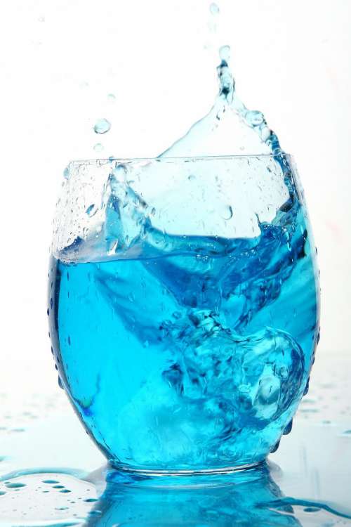 Ice splashes into blue beverage