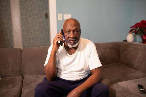 Man Talking on Mobile phone sitting at home - looking at camera