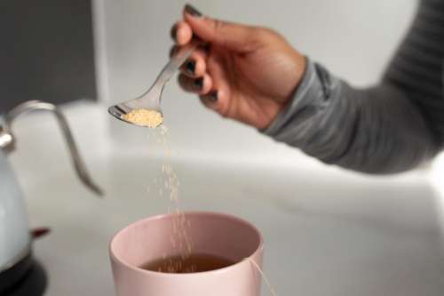 Unrecognizable Woman Hand adding sugar into tea cup