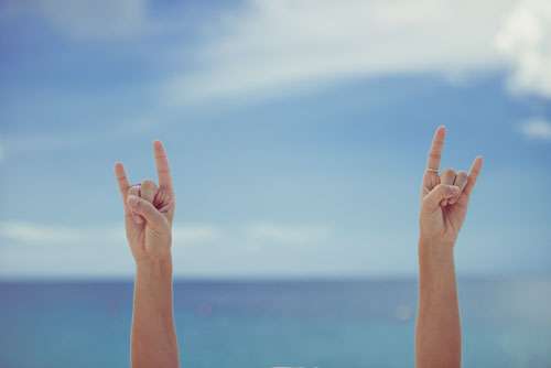Girls Hands Giving Horns Sign On A Summer Beach With Ocean
