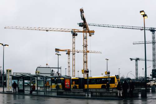 Cranes Hover Over Buses Photo
