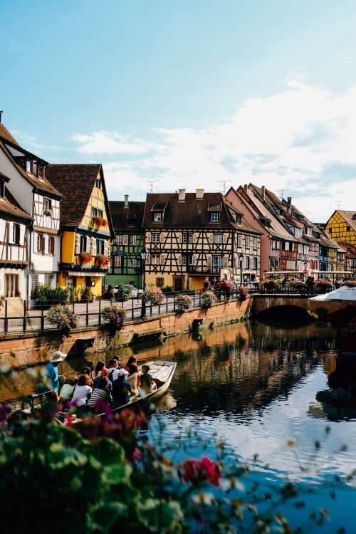 Boat Cruises Along River Overlooked By Town Photo