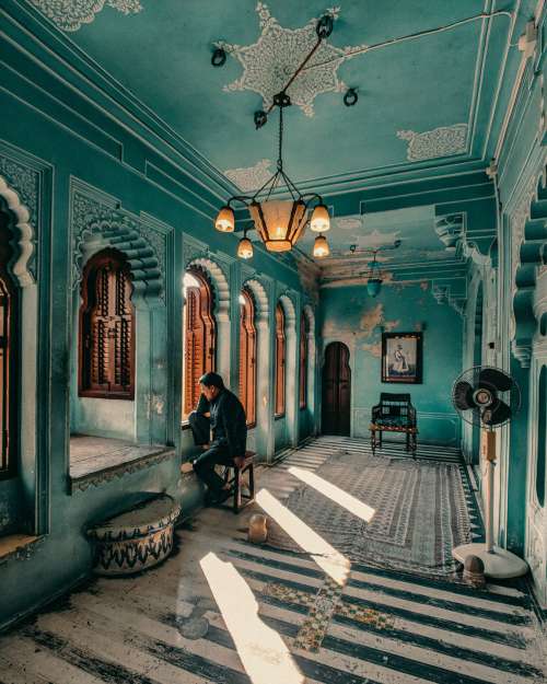 Man Sits Within Ornate Blue Hallway Photo