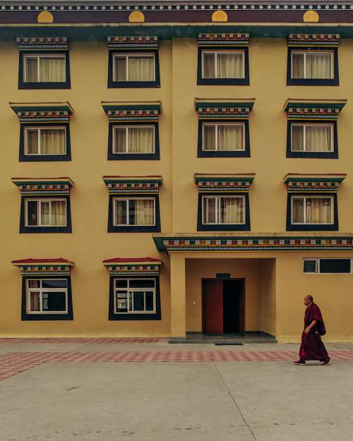 Buddhist Monk Walks By Yellow Building Photo