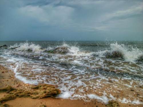 Sea waves crashing on rocks and cloudy sky