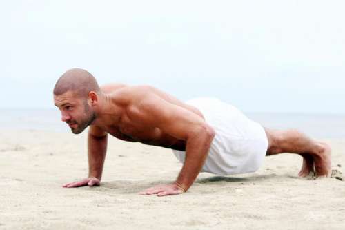 Fit man doing pushups on the beach