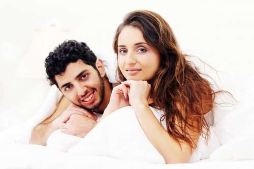 Young couple sitting up in bed