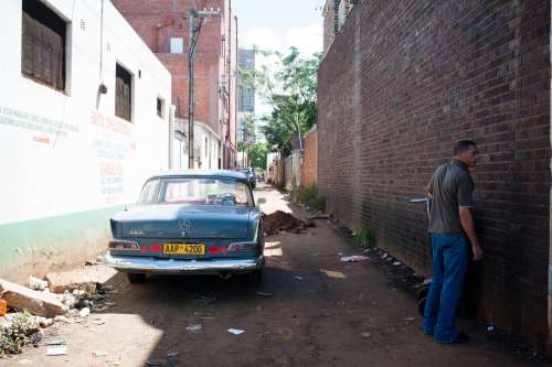 people, neighborhood, street, car, vehicle, road, path, parking, houses, man