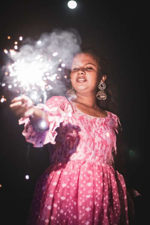 Young Woman Holds Out Sparkler Photo