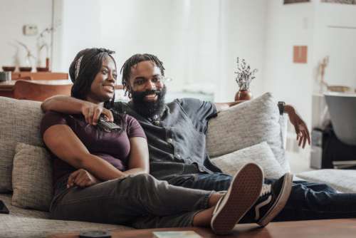 Smiling Couple On Couch Watching TV Photo