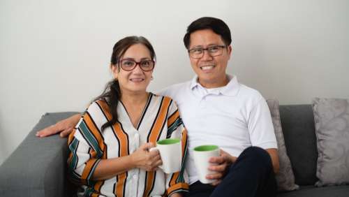 Couple Sitting On Couch With Coffees Photo