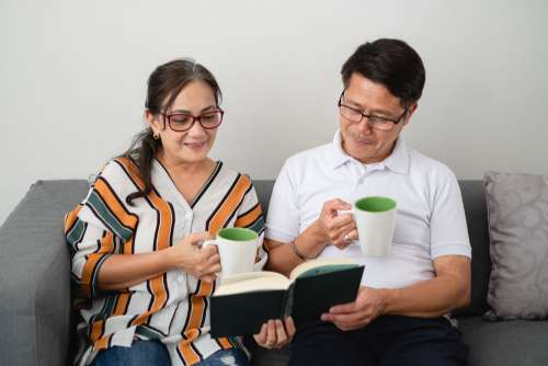 Two People Read A Book Sitting On A Couch Photo