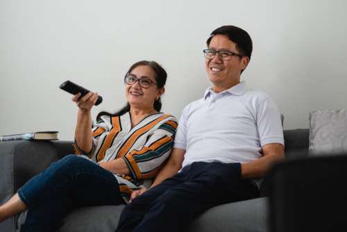 Couple Watches Television On Grey Couch Photo