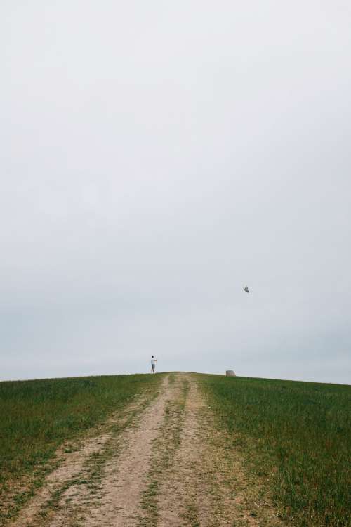 Person Stands On Hill And Flies A Kite Photo