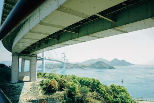 Reaching Bridge Over Water And Mountians Photo