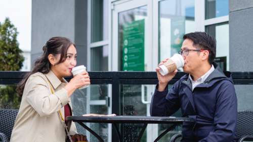 Two People Sip From Takeout Cups On A Patio Photo