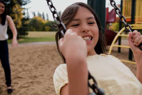 Child Smiles Big On Swing Set Photo