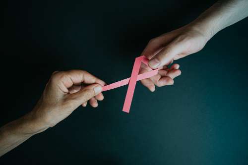 Two Hands Hold Each End Of Pink Ribbon Photo