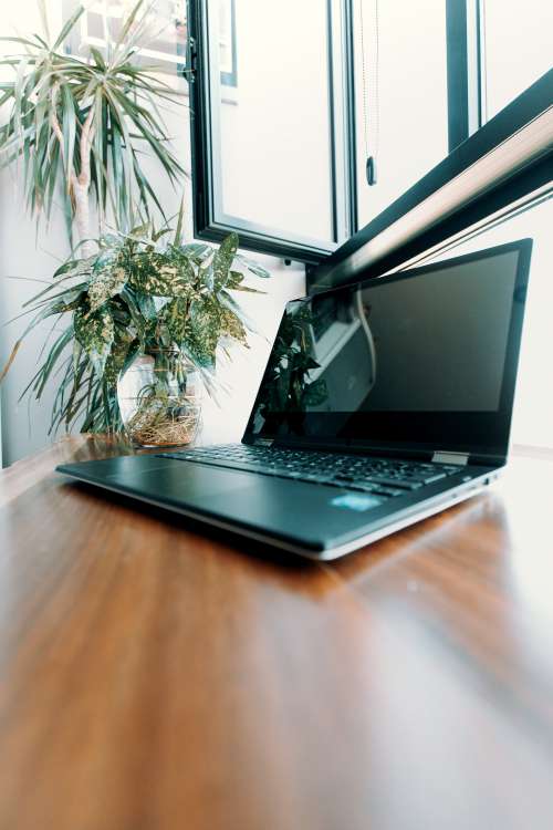 Open Laptop On A Wooden Desk Under Window Photo