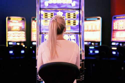 Young woman playing at slot machine in casino. Gambling concept.