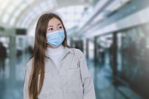 Coronavirus corona virus Asian woman wearing flu mask walking on work commute in public space transport train station