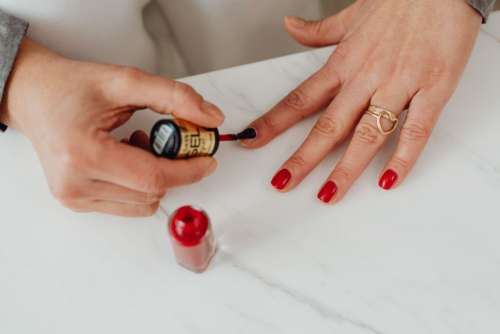 Closeup of a woman painting her nails with red nail polish