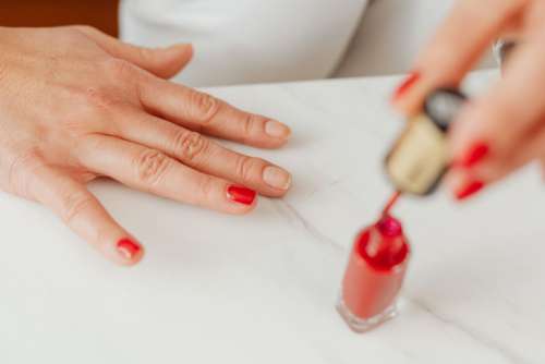 Closeup of a woman painting her nails with red nail polish