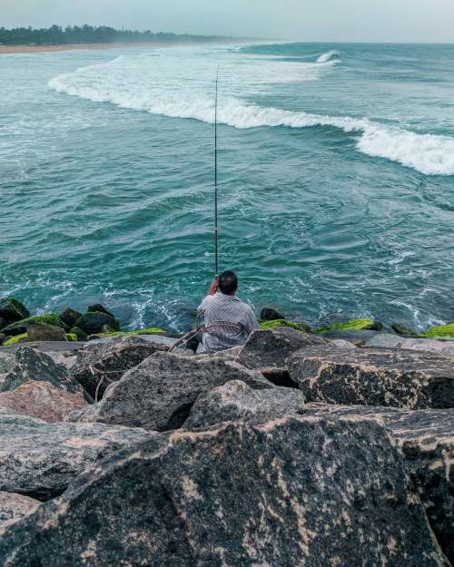 Person With Fishing Rod Of Mossy Green Rocks Photo