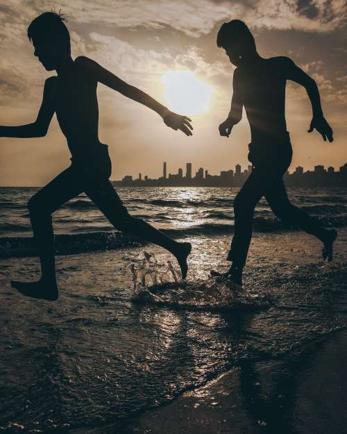 Silhouettes Of Two People Splashing On The Beach Photo