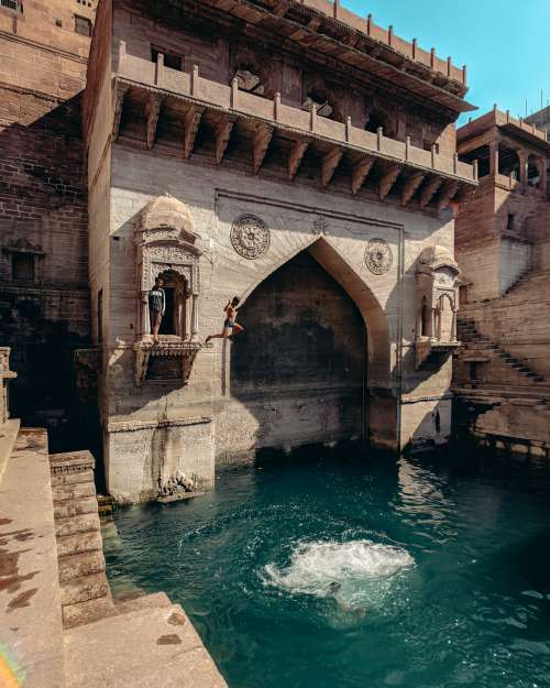 People Jump Into The Water From A Stone Alcove Photo