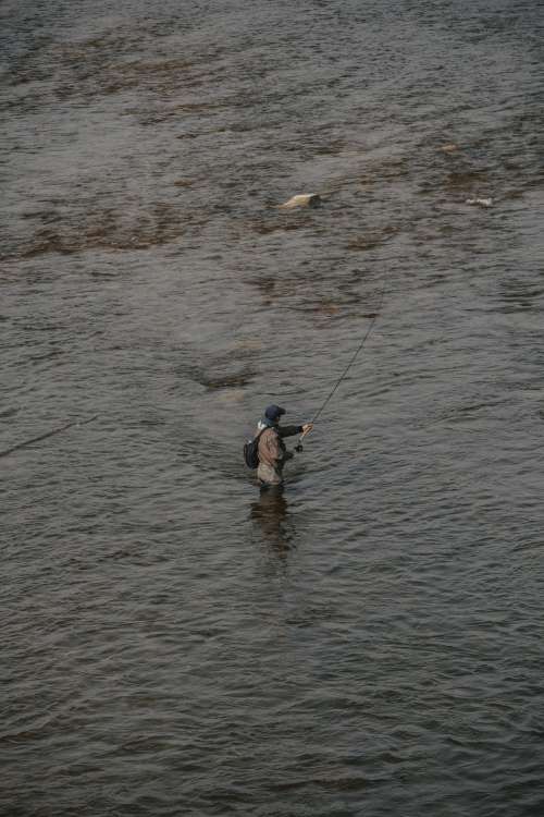 Man Standing In The River With A Fishing Rod Photo