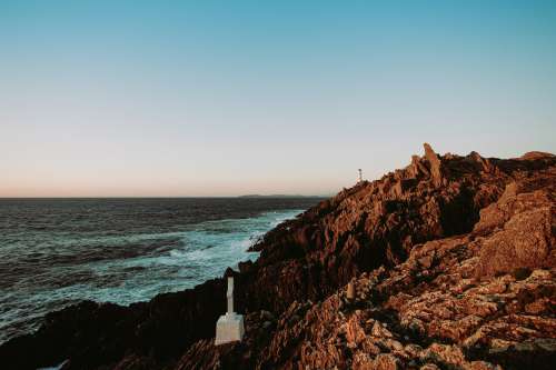 A Lighthouse Sits On Top Of A Cliff Photo