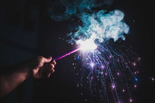 Person Holds Lit Firework With Purple Smoke Photo
