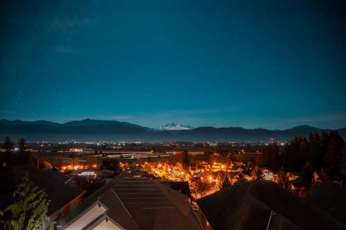 Town Looks Out To Snow Capped Mountains And A Starry Sky Photo