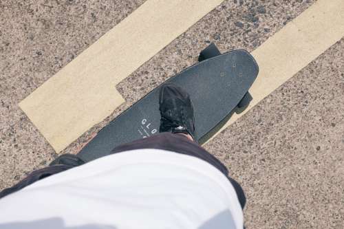 Person Standing On A Black Skateboard On A Paved Road Photo