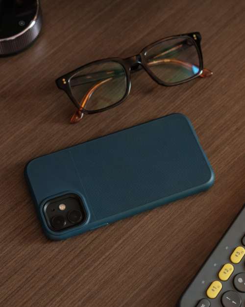 Blue Phone Case And Eyeglasses On Wooden Table Photo