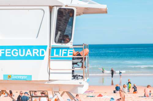 A Lifeguard Sits In Raised White Stand Photo