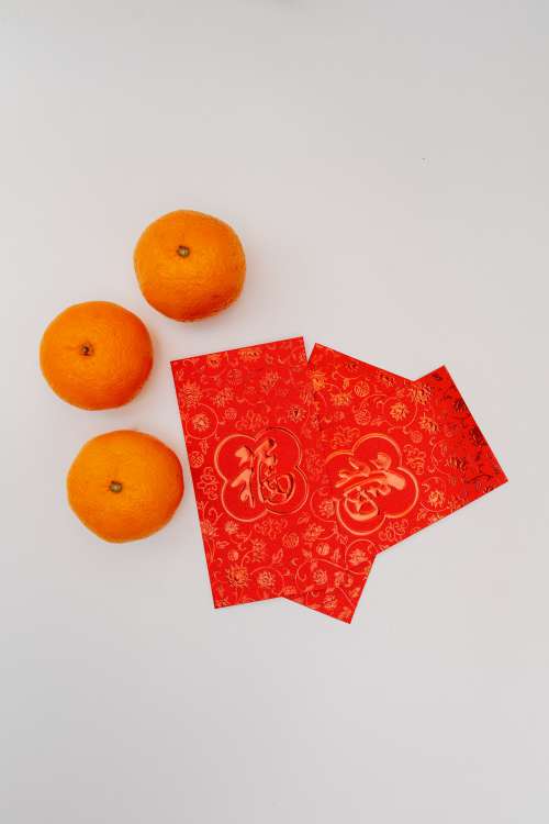 Three Oranges And Three Fanned Out Red Cards On White Photo