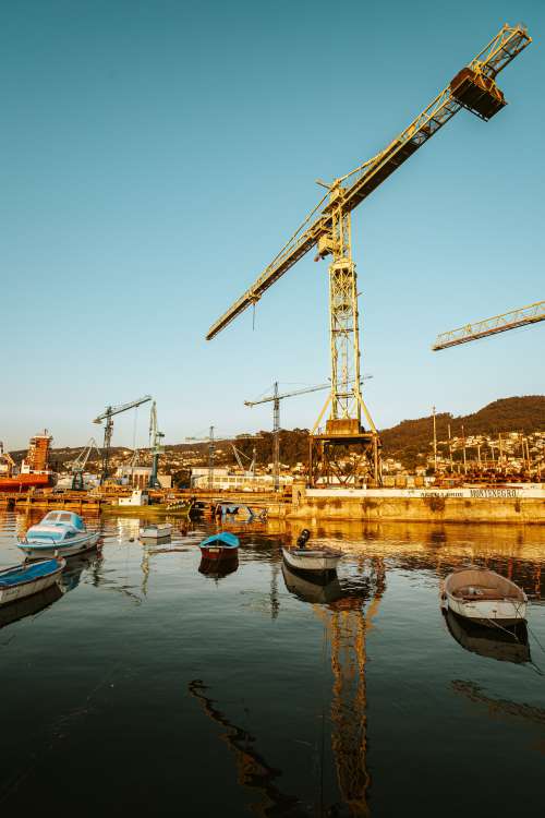 Boats And Cranes Lit By A Rising Sun Photo